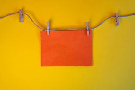 Empty orange paper card on yellow wall, minimal festive design with copy space. Perfect for Halloween or seasonal greeting mockups.の写真素材