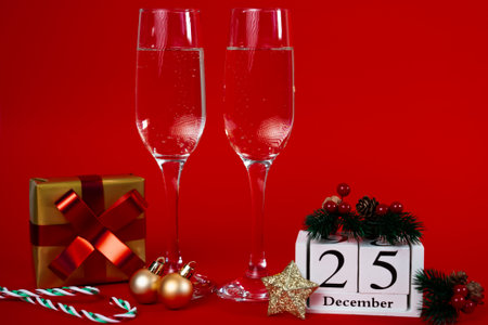 Festive red holiday arrangement featuring champagne flutes, ornaments, gift and block calendar...