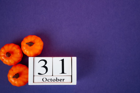 Creative Halloween composition with pumpkins and October 31 wooden calendar on purple background. Ideal for seasonal advertising and design.の写真素材