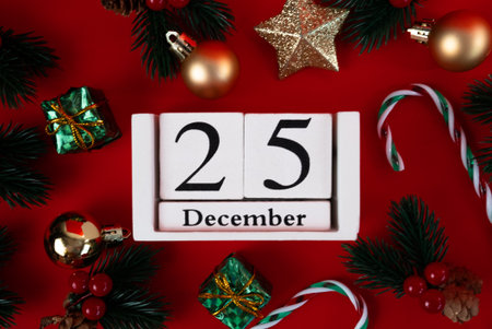 Holiday flat lay with December 25 wooden calendar, candy cane, golden stars and gifts on red backdrop. Perfect for Christmas marketing.の写真素材