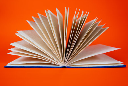 Education concept with open book and fanned pages on red backdrop. Ideal for study, literature, research and knowledge themes.の写真素材