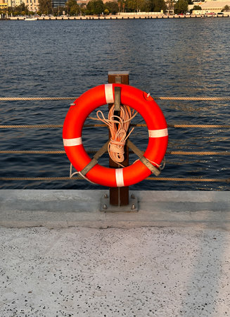 Bright red lifebuoy floating near the shore, symbolizing safety, rescue, and protection. Perfect for...