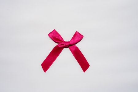 Clean pink ribbon bow on white background. Decorative element for gift, packaging, seasonal and craft visuals.の写真素材