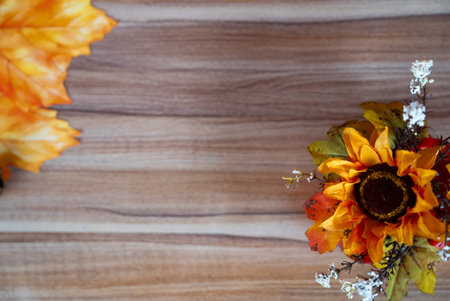 Close-up autumn sunflower with leaves and seasonal decor on rustic wooden background. Perfect for Thanksgiving and fall mood.の写真素材