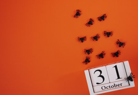 Spooky Halloween flat lay with October 31 calendar and black spiders crawling on orange background. Perfect for eerie holiday designs.の写真素材