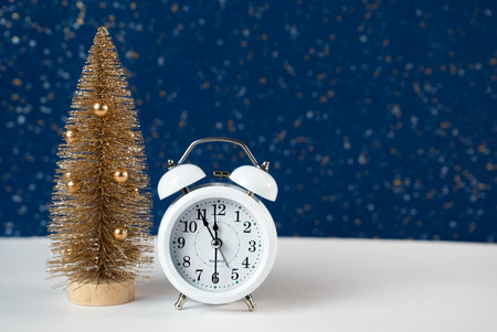 Festive blue background with white clock and decorative tree symbolizing New Year celebration and holiday spirit.の写真素材