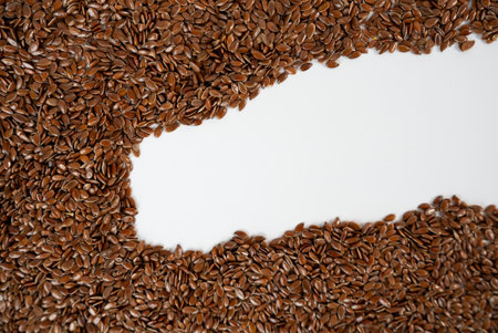 Brown flax seeds arranged in frame on white, ideal for healthy lifestyle, vegan, and diet-related projects.の写真素材
