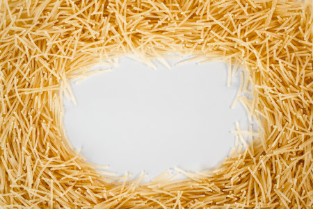 Golden raw vermicelli pasta arranged in circular frame on white background. Ideal for Italian cuisine, food blogs, and product packaging.の写真素材