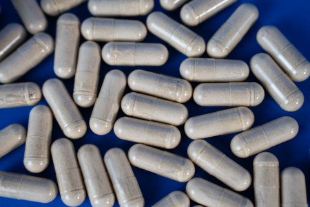 Close-up of white medical capsules on a blue surface. Ideal for health, pharmacy, or supplement industry visuals. High quality photoの写真素材