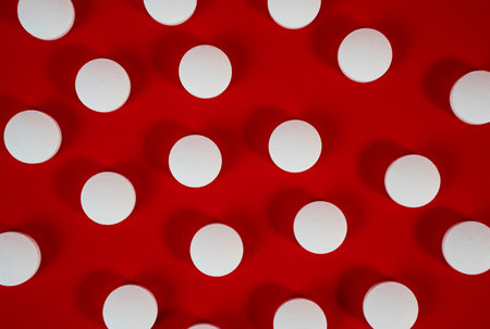 Dense field of white round tablets covering a red surface, minimal texture shot for backgrounds and health concepts. High quality photoの写真素材