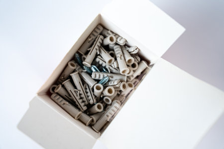 Open box filled with assorted wall plugs and screws on a white background. Construction and home repair supplies, hardware tools. High quality photoの写真素材