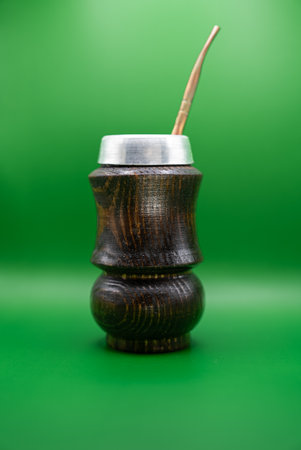 Studio shot of traditional yerba mate cup with metal straw on green background. Symbol of natural energy, Latin lifestyle, and wellness culture.の写真素材