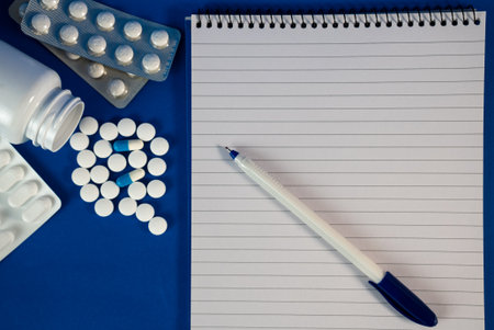 Flat lay of pills, bottle, and notebook on colorful surface. Great for healthcare, telemedicine, or pharmacy. High quality photoの写真素材