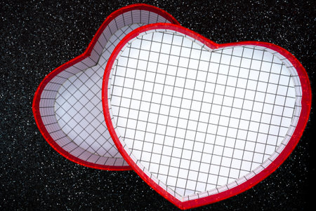 Red heart shaped gift box with textured lid on dark glitter background. Romantic minimal concept for Valentine Day, love message, wedding or holiday promotion with copy space.の写真素材