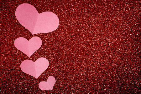 Soft pink paper hearts floating on red glitter background. Minimal romantic Valentine Day backdrop...