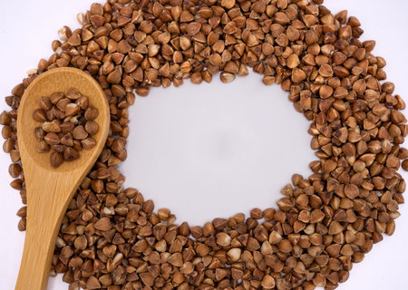 Creative composition of buckwheat groats arranged in a circular frame with wooden spoon. Healthy food background with copy space.の写真素材