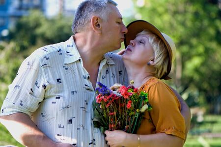 Men and women kissing in the park holding the flowersの写真素材