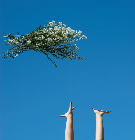 Hands and a bunch of flowers against skyの写真素材