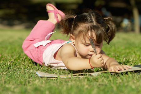 girl paints in a park lying on the grassの写真素材