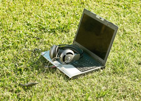 laptop and earphones in a park on the grassの写真素材