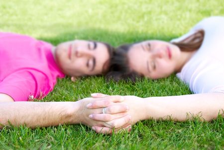 beauty young caucasian couple laying on grass holding handの写真素材