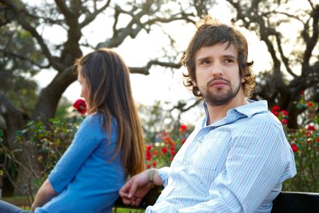 Man and woman sitting on opposite sides of park benchの写真素材