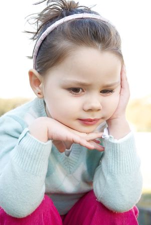 Beautiful little girl thinking in the park