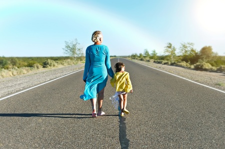 Mother and daughter are walking far away on rural road in summer dayの写真素材