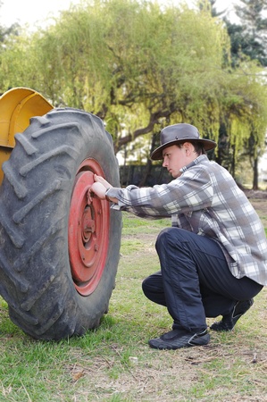 Handsome next to a tractor wheel fixingの写真素材