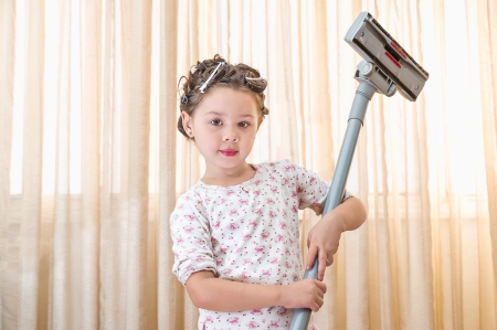 Young Girl with a vacuum cleaner in her roomの写真素材