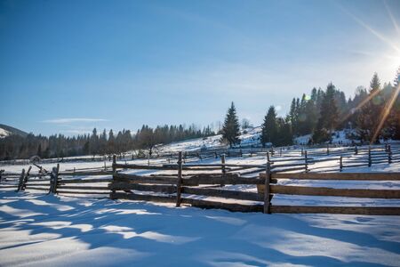 fence in sunny winter forest, a lot of snow white and fluffy, beautiful bright sunny rays of the...