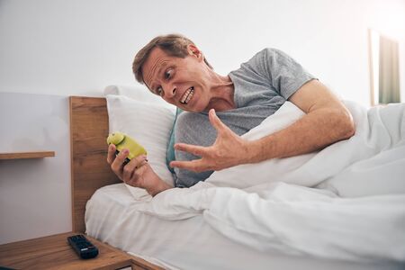 Angry male person shouting at alarm clockの写真素材