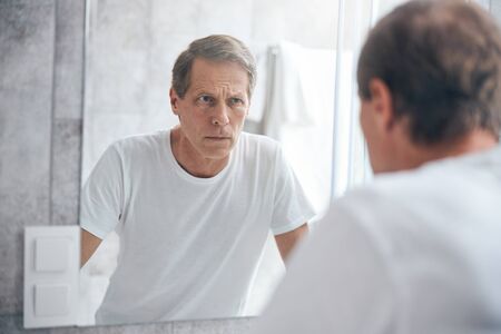 Sad person examining himself in the mirrorの写真素材