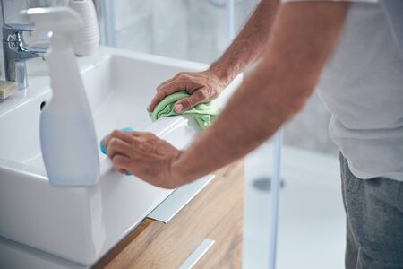 Man with a cloth standing at the sinkの写真素材