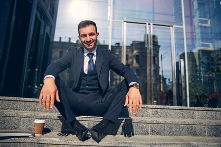 Attractive brunette male sitting outside near beautiful buildingの写真素材