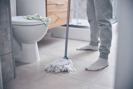 Male in cotton socks holding a mop
