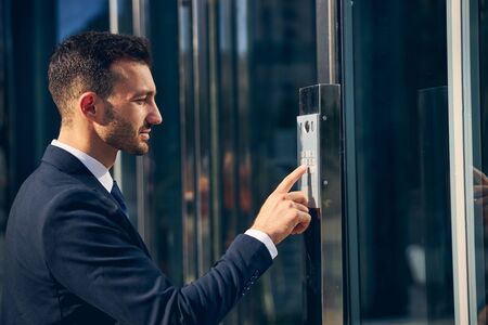 Serious brunette man trying to enter building