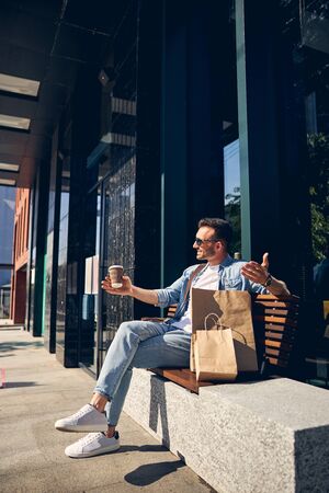 Positive delighted young man waiting his friendの写真素材