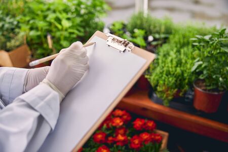 Cropped photo of a biological scientist holding a clipboard and a pencil with both handsの写真素材