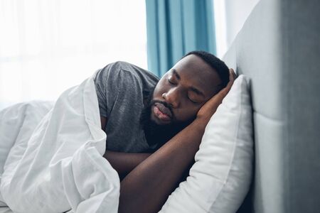 Tired international male person sleeping in his bed