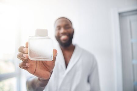 Close up of happy man that demonstrating his favourite bottleの写真素材