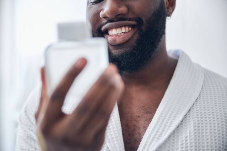 Kind dark-skinned male person feeling happiness while preparing for romantic date, wearing bathrobeの写真素材