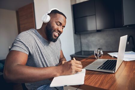 Cheerful bearded man making notes in notebookの写真素材