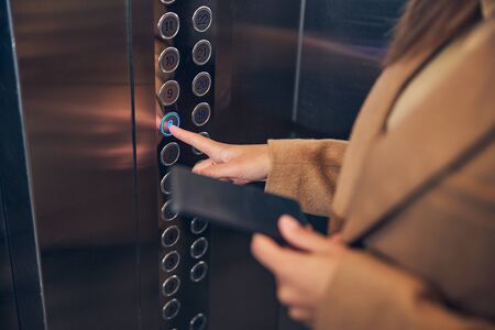 Female staying in lift and holding her mobile