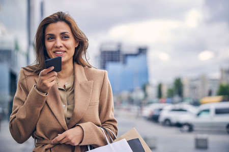 Smiling lady with a gadget looking into the distanceの写真素材