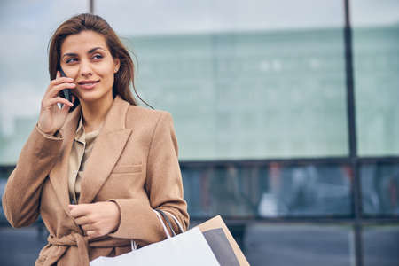 Pleased lady having a phone conversation outsideの写真素材