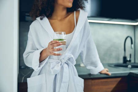 Slim woman holding a glass of cucumber drink