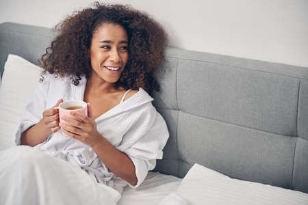 Cheerful African American woman sitting in bed