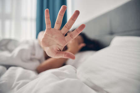 African  lady covering her face in bed