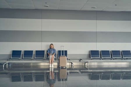Joyful female person sitting in departure loungeの写真素材